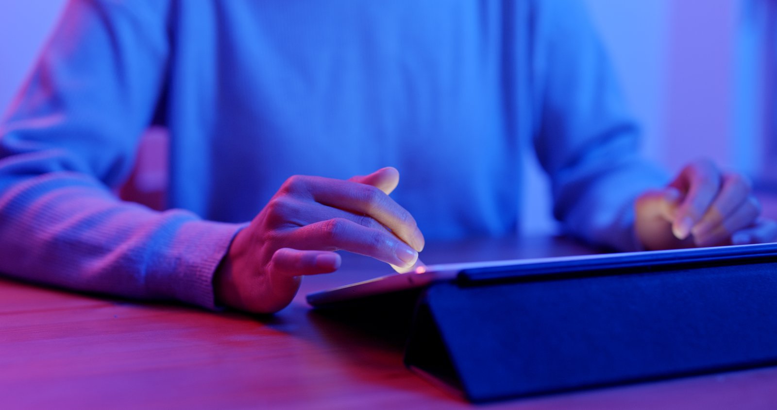 People collaborating with a tablet in blue and purple light